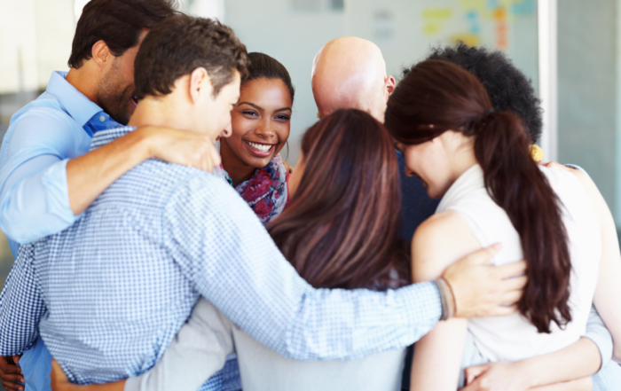 Grupo de empleados abrazados tras llevar a cabo una dinámica de team building para empresas