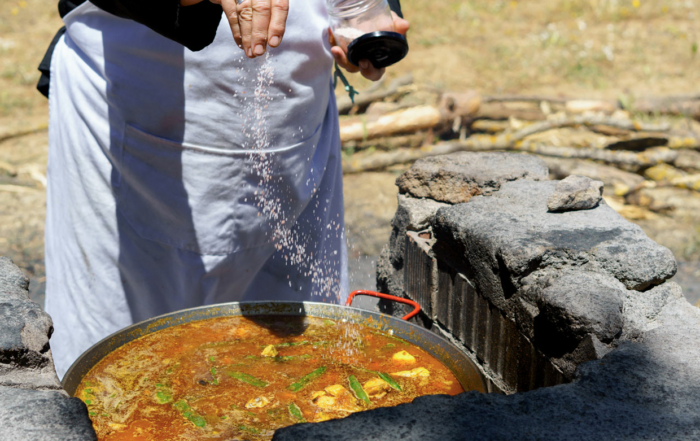 Mujer echa sal a la paella en un taller de cocina para empresas en Valencia